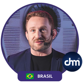 Fotografía de Andrea Iorio durante una conferencia, con micrófono de diadema, fondo moderno y gesto expresivo.