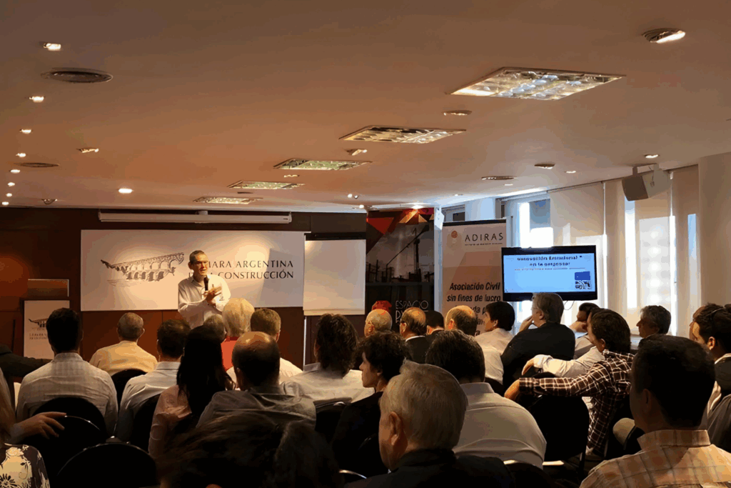 Fotografía de Daniel Colombo impartiendo una conferencia sobre innovación emocional en los negocios, frente a un público en un salón de la Cámara Argentina de la Construcción.