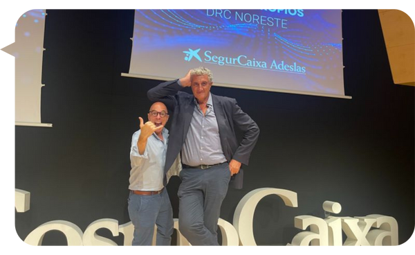 Diego Antoñanzas junto a un colega en el escenario, ambos en una pose divertida durante un evento de SegurCaixa Adeslas.