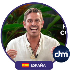 Fotografía de Ferran Tort en una conferencia, con expresión entusiasta, vistiendo camisa clara y collar artesanal, sobre un fondo natural con vegetación tropical.