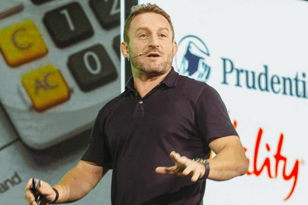 Fotografía de Andrea Iorio durante una presentación en vivo, con micrófono de diadema, frente a una pantalla proyectando el logotipo de Prudential y gráficos de una calculadora.