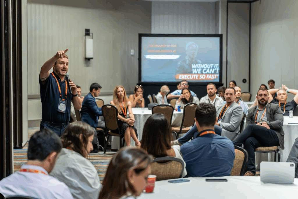 Fotografía de Andrea Iorio impartiendo una charla interactiva en una sala de conferencias, rodeado de asistentes atentos durante un evento profesional.