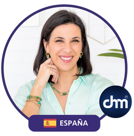 Fotografía de Gemma Ramírez sonriendo, con camisa celeste y accesorios dorados, sentada en un entorno iluminado y moderno con detalles decorativos.