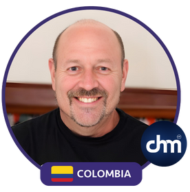 Fotografía de un conferencista sonriente calvo con barba de candado, vestido con camiseta negra, sobre un fondo interior con iluminación cálida. Imagen enmarcada con diseño gráfico que indica "Colombia" y el logotipo de Digital Health Management (CHM).