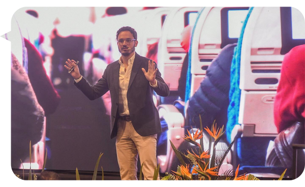 Borja Castelar dando una conferencia frente a una pantalla grande que muestra la imagen de un avión por dentro.