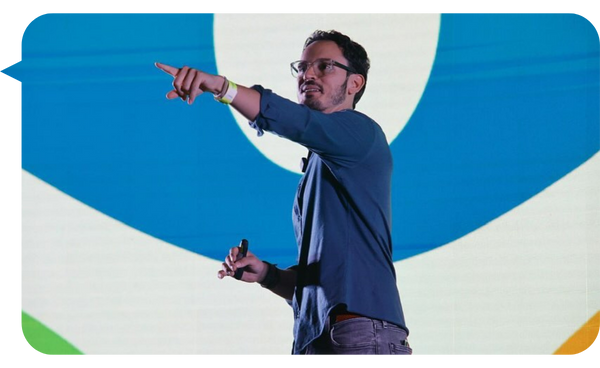 Borja Castelar señalando al público durante una conferencia, con una gran pantalla colorida de fondo.