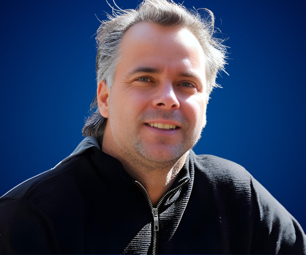 Fernando González sonriendo, extenista chileno, con fondo azul institucional.