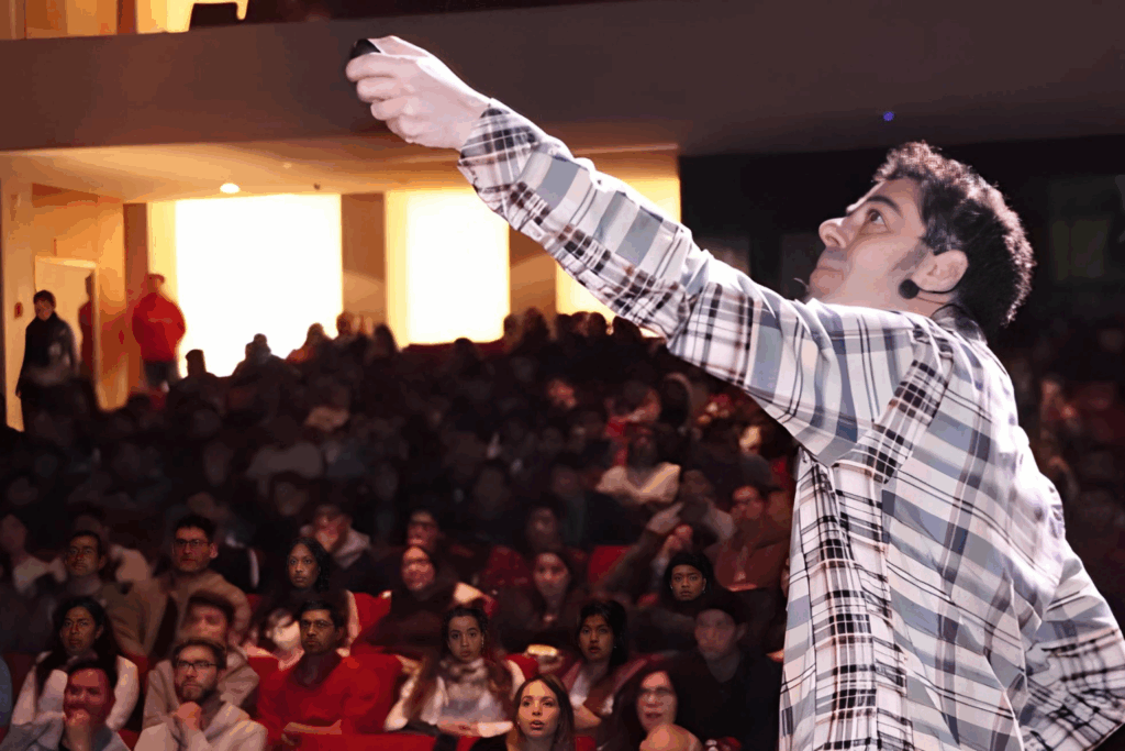 Fotografía de Gabriel Gurovich impartiendo una conferencia en un auditorio lleno, levantando la mano con un control remoto mientras se dirige a la audiencia.