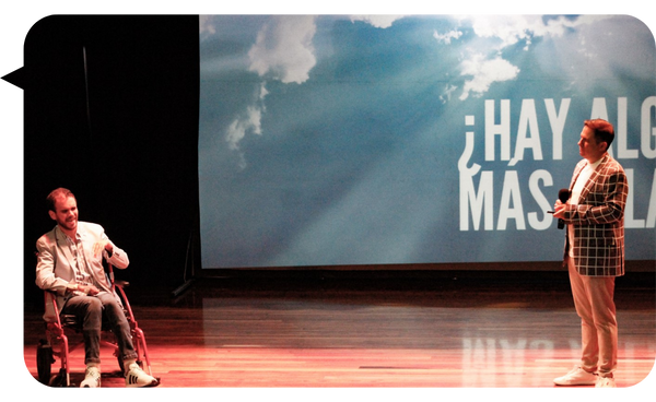 Kike y Gino en el escenario durante una conferencia, con un fondo que muestra la frase "¿Hay algo más allá?"