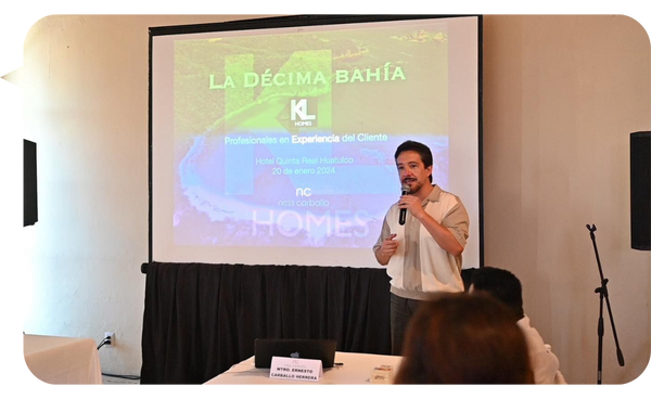 Ness Carballo, conferencista internacional, presentando en un evento sobre experiencia del cliente, con una pantalla de proyección al fondo que muestra el título 'La Décima Bahía'.