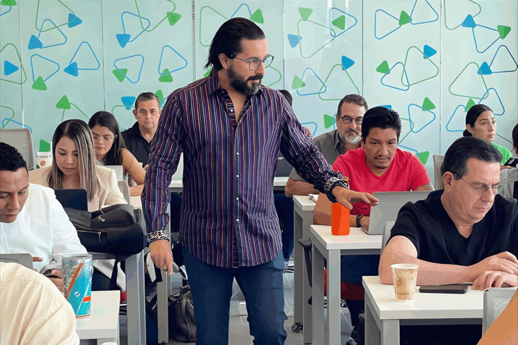 Fotografía de Daniel Villarreal impartiendo un taller interactivo, caminando entre los asistentes y brindando asesoría personalizada en un aula moderna.