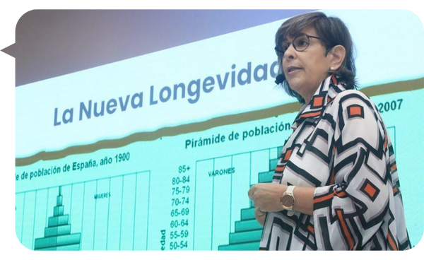 Carmen Álvarez Basso, conferencista, presentando un tema titulado "La Nueva Longevidad" frente a una pantalla grande.