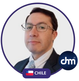 Fotografía de Rodrigo Rivera, conferencista chileno, posando con expresión seria y profesional, usando gafas, traje oscuro y camisa clara con corbata formal, sobre fondo blanco.