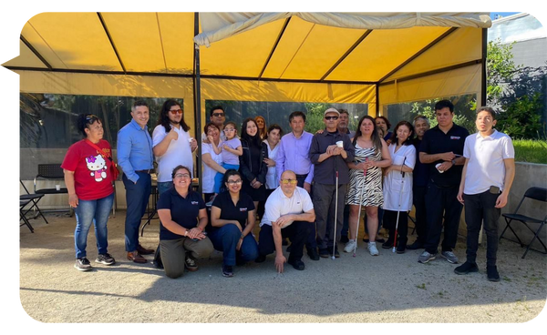 José Cuadra posando con un grupo de personas en una actividad comunitaria al aire libre.