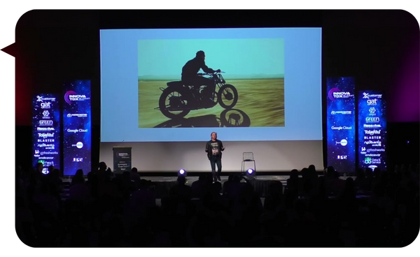 "Alexis Socco presentando una diapositiva con la imagen de una motocicleta en una conferencia"