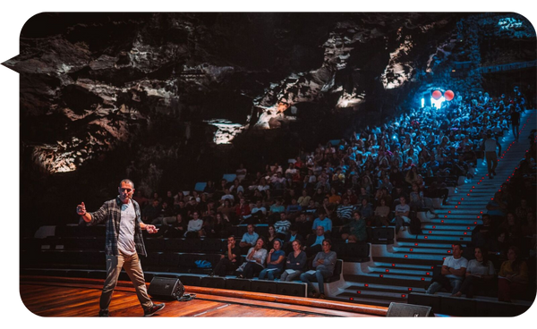 "Álvaro Vizcaíno dando una charla en una sala con iluminación tenue, frente a una audiencia numerosa."