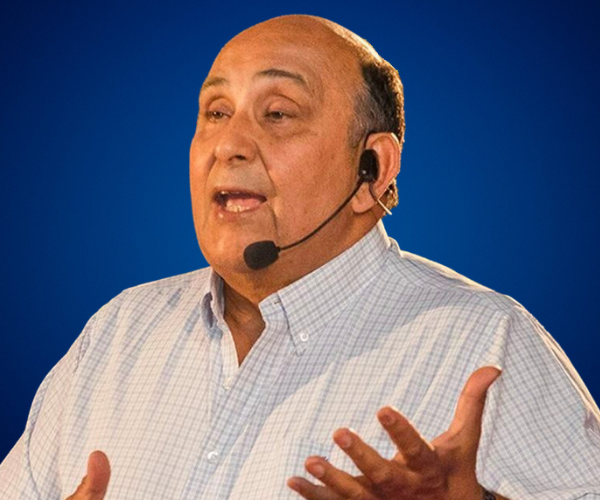 Antonio Vizintín hablando en una conferencia, usando un micrófono de diadema y gesticulando mientras se dirige a su audiencia.