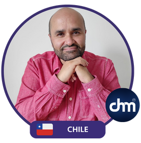 Imagen de Fernando Veliz Montero, conferencista y consultor chileno, con una camisa roja, apoyando sus manos bajo su mentón, con el logo de Dhm y la bandera de Chile en la parte inferior.