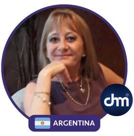 Mónica Reta, coach de vida y conferencista internacional, posando con una sonrisa. Imagen circular con la bandera de Argentina y un logotipo en la esquina inferior derecha.