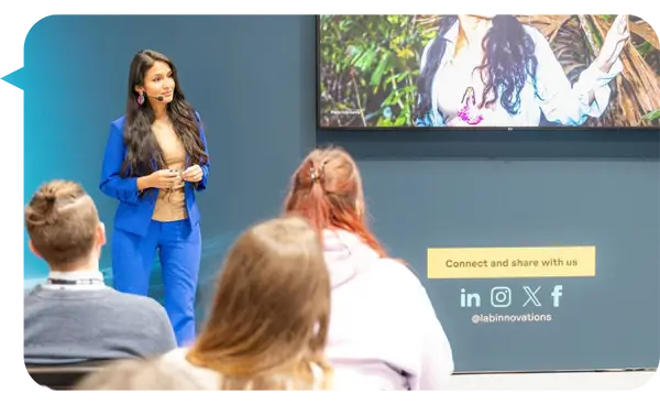 Dra. Rosa Vásquez Espinoza presentando en un evento de innovación, vestida con un traje azul, frente a una audiencia.