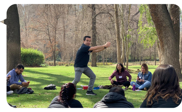 Julián Mendiola liderando una dinámica al aire libre con un grupo de personas, en un entorno natural durante una jornada de formación en liderazgo y trabajo en equipo.