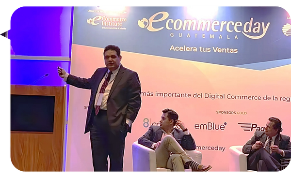 Leo Rodríguez en el escenario del evento Ecommerce Day Guatemala, señalando una presentación mientras habla al público.