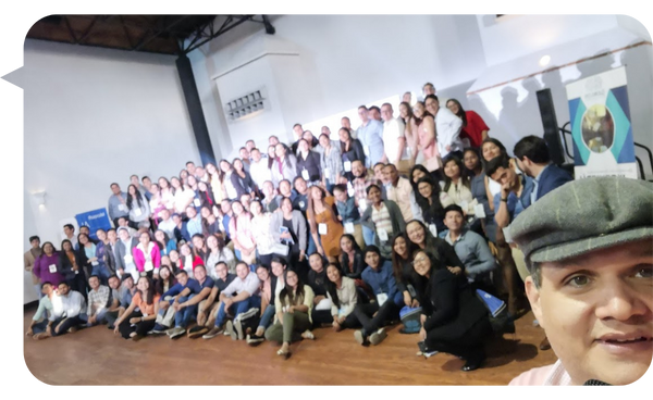 Leo Rodríguez toma una selfie frente a un gran grupo de personas en un evento, todos posando para la foto en un espacio amplio.