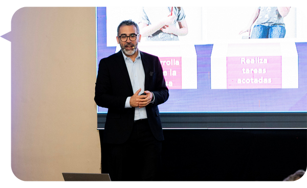 Martín Quirós presentando una conferencia sobre liderazgo y gestión empresarial, con gráficos en el fondo.