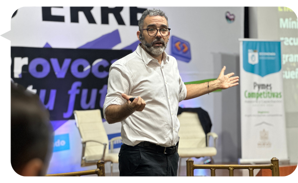 Martín Quirós impartiendo una conferencia sobre gestión empresarial para Pymes y empresas familiares, con fondo corporativo.