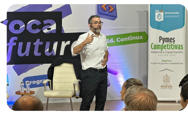 Martín Quirós impartiendo una conferencia sobre Pymes competitivas y desarrollo empresarial, con audiencia al frente y fondo corporativo.