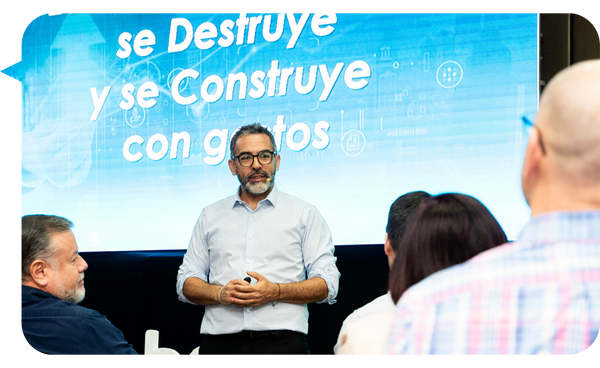 Martín Quirós en una conferencia sobre desarrollo empresarial, con un mensaje proyectado de fondo y audiencia atenta.