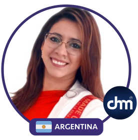 Rita Vieyra, psicóloga organizacional y conferencista internacional de Argentina, sonriendo con una chaqueta blanca y el logo de CHM al fondo.