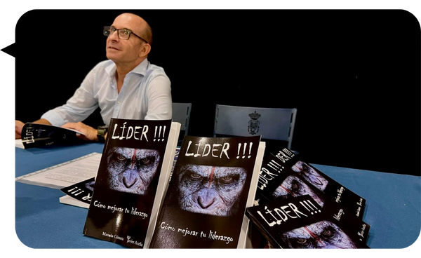 Manolo Cámara sentado en una mesa junto a varios ejemplares de su libro "Líder!!! Cómo mejorar tu liderazgo".