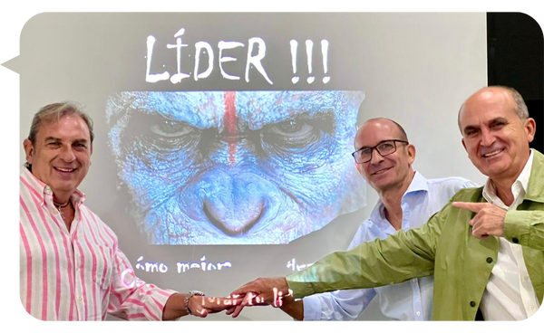 Manolo Cámara junto a dos personas señalando la portada de su libro "Líder!!! Cómo mejorar tu liderazgo" proyectada en una pantalla.