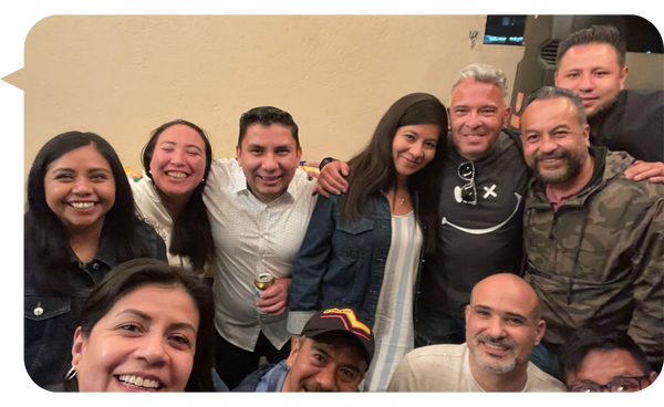 Adolfo Alvarez León sonriente junto a un grupo de personas en un ambiente relajado y amistoso.