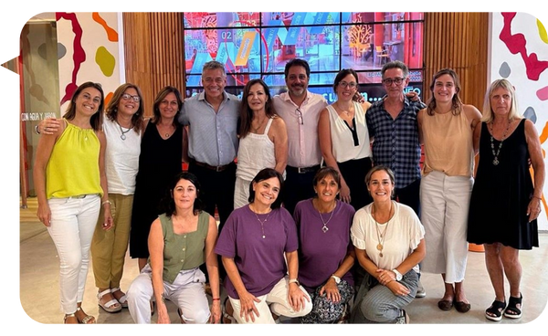 Alejandro Delobelle posando con un grupo de participantes después de una conferencia o taller, en un ambiente colaborativo y colorido.