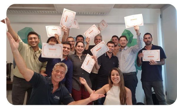 Alejandro Delobelle celebrando con un grupo de participantes que sostienen sus certificados de finalización tras un taller.