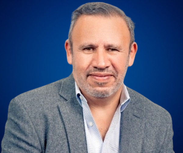 Retrato de Franco Borges, conferencista y coach internacional, con fondo azul.