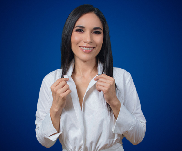 Gabriela Téllez sonríe con confianza mientras viste una camisa blanca, destacándose sobre un fondo azul, representando profesionalismo y cercanía.