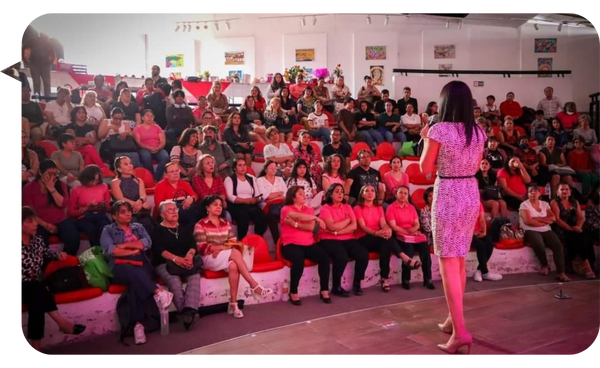 Gabriela Téllez dirige una conferencia ante una audiencia diversa, fomentando la participación activa y el aprendizaje en temas de inteligencia emocional.