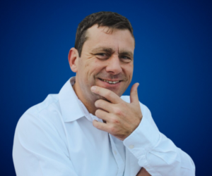 José Illescas sonriendo y posando en una imagen con fondo azul.