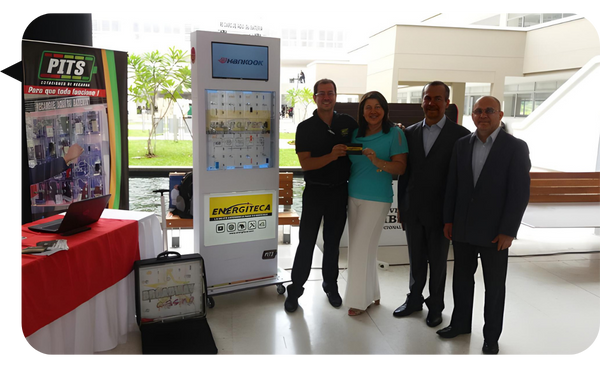 Cinco personas posan sonrientes junto a una exhibición de productos tecnológicos en un evento empresarial.