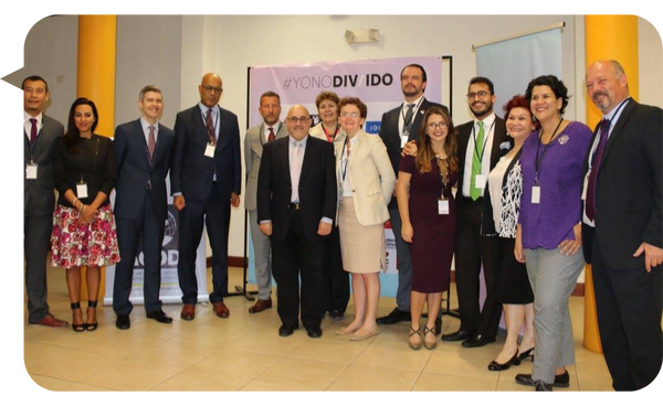 : Grupo de profesionales y expertos posando durante un evento sobre inclusión y diversidad, con un cartel de fondo que dice "#YoNoDIVido".