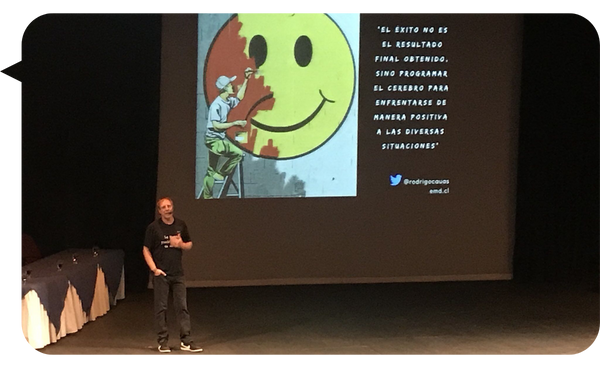 Rodrigo Cauas Esturillo en una conferencia, con una imagen de motivación proyectada en pantalla.