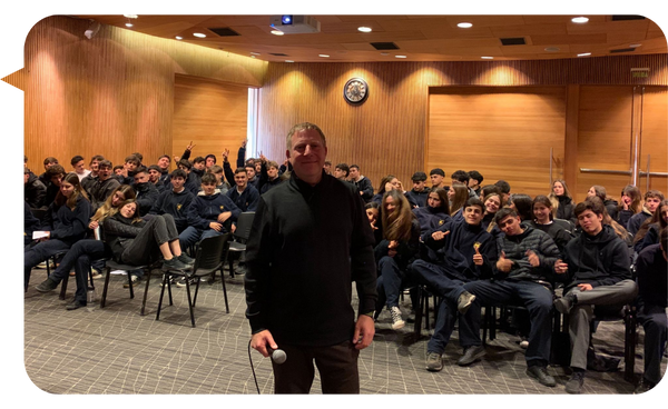 Rodrigo Cauas Esturillo, psicólogo deportivo, posando frente a un grupo de estudiantes durante una conferencia.