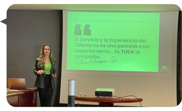 "Yami Almaguer Gil dando una presentación sobre Experiencia del Cliente, con una proyección de una frase destacada en la pantalla."