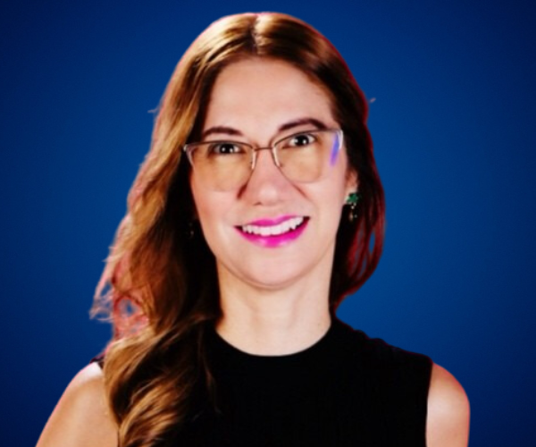 "Yami Almaguer Gil sonriendo, usando gafas y vestida de negro, con un fondo azul."