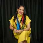 Ivonne Casado, conferencista internacional, sentada con vestido amarillo y gesto sereno, en una imagen que refleja autenticidad y poder interior.