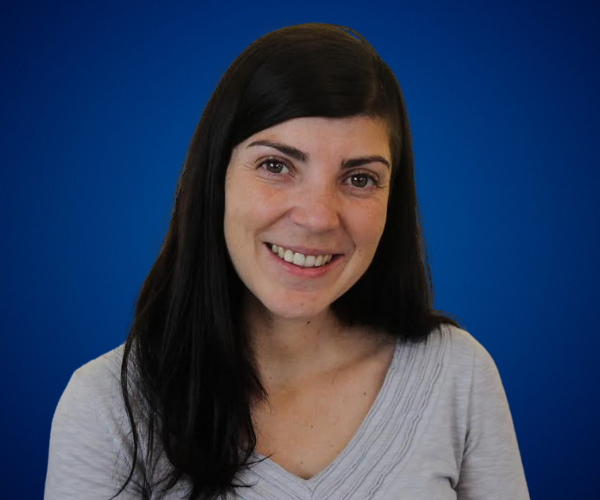 Fotografía de Bárbara Padilla, conferencista, montañista y escritora, sonriendo con fondo azul.