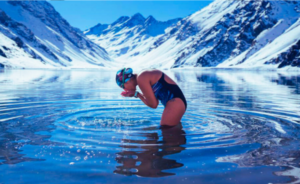 Bárbara Hernández en aguas gélidas rodeada de montañas nevadas, preparándose para nadar.